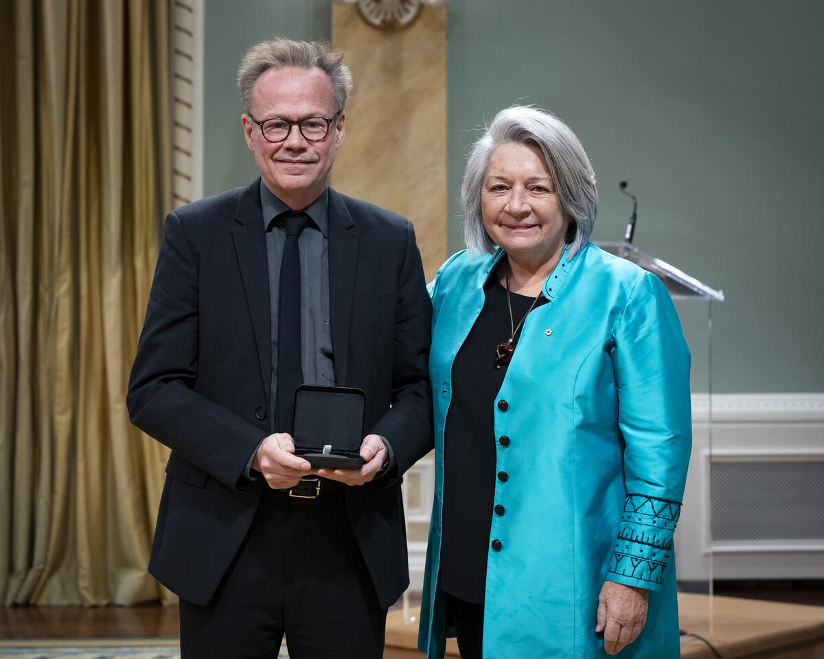 La gouverneure générale Mary Simons pose avec un homme qui tient un étui à médaille ouvert.