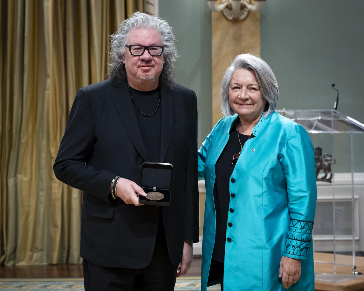 La gouverneure générale Mary Simons pose avec un homme qui tient un étui à médaille ouvert.