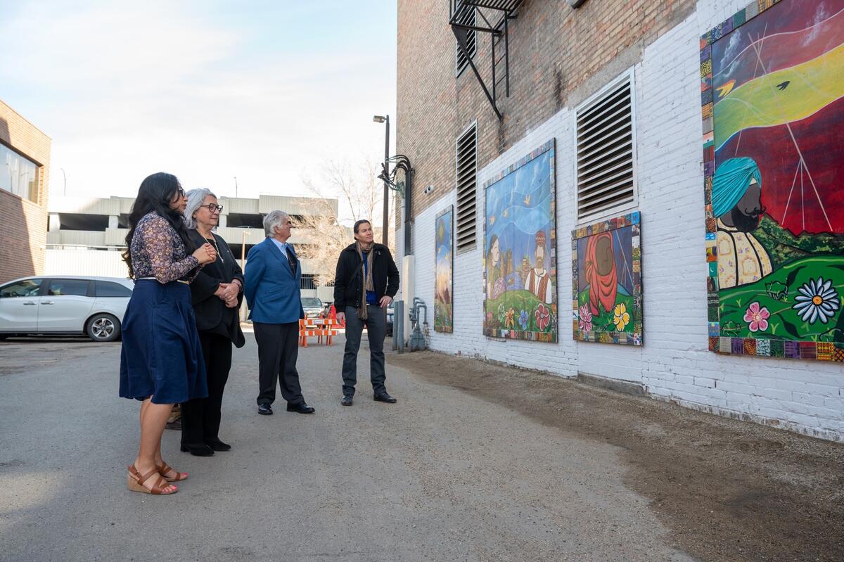 Governor General Simon, Mr. Whit Fraser and two other people standing in front of a large mural.