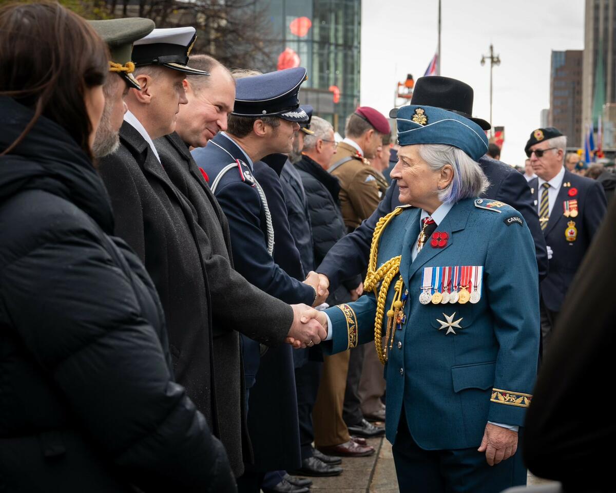 La gouverneure générale Mary Simon, en uniforme de l'armée de l'air, serre la main d'un participant à la cérémonie du jour du Souvenir.